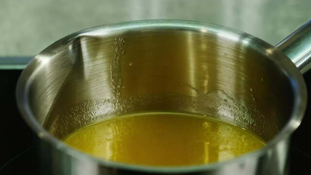 Mixture of juice and gelatin heated in saucepan on stove to desired temperature. Gelatin dissolves in juice due to heat