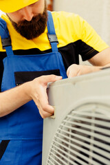 Close up of seasoned repairman installing condenser after replacing faulty unit. Adept worker...