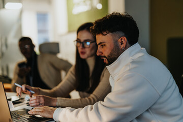 Diverse colleagues collaborate late in the evening, discussing business growth, market expansion,...