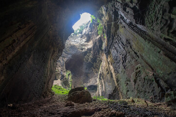 View from inside a cave looking out towards the entrance with natural light streaming in
