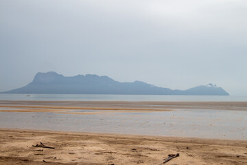 Fototapeta na wymiar A serene beach view with distant mountains shrouded in haze.