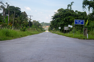 Empty road leading towards Fairy Cave with surrounding greenery and directional signage.