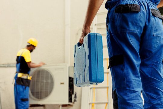 Electrician arriving on location to help wireman fix system electrical issues caused by faulty wiring or defective capacitor requiring professional intervention to diagnose and repair