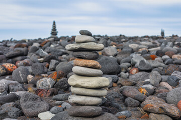 Pebble beach with pyramid of stones . Stacked stones on the ocean coast 