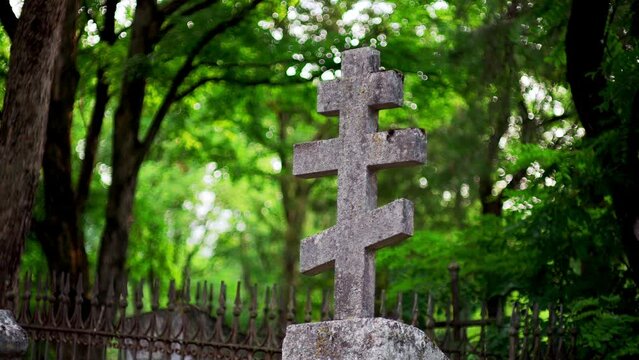 Deep in forest lies tranquil spot, where old, haunting concrete cross stands in midst of graveyard. It serves as final resting place for soldiers and civilians from World War