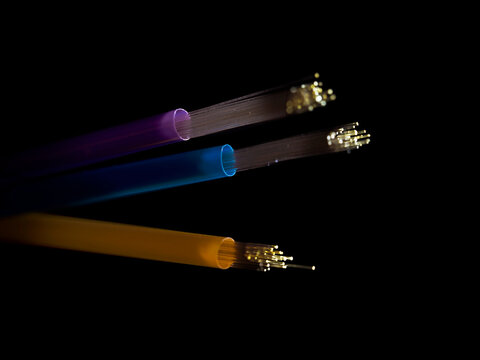 Fibre optic LED lights threaded through three straws against a black background