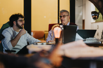 Colleagues brainstorming and discussing business growth, marketing opportunities, and profit growth. Multi-generational and multiethnic team working together to strategize and plan for success.