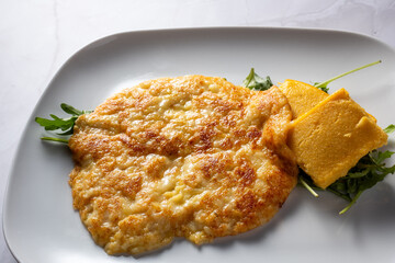 detail frico with potatoes, typical Friulian gastronomy. white marble background