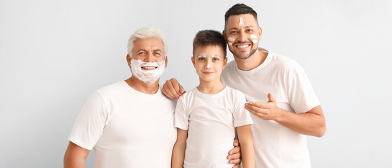 Man, his father and son with shaving foam on their faces on light background - obrazy, fototapety, plakaty