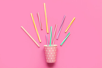 Paper cup with different drinking straws on pink background