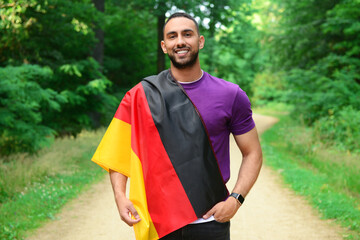 Young man with flag of Germany in forest