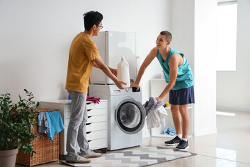 Male students doing laundry in dormitory - obrazy, fototapety, plakaty