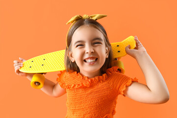 Cute little girl with skateboard on orange background