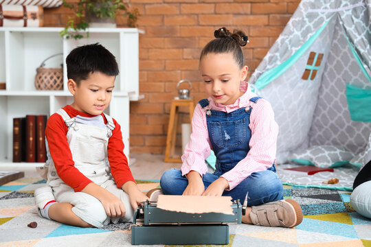 Cute little children with typewriter at home