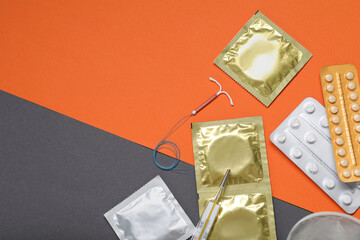Contraceptive pills, condoms, intrauterine device and thermometer on color background, flat lay...