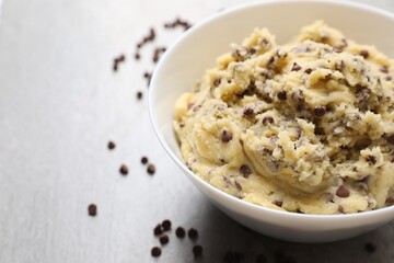 Chocolate chip cookie dough in bowl on light gray table, closeup. Space for text