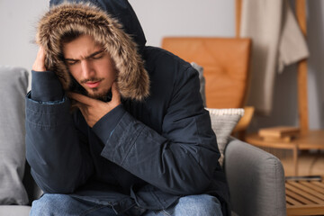 Frozen young man in puffer jacket at home © Pixel-Shot