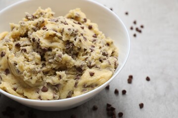 Chocolate chip cookie dough in bowl on light gray table, closeup