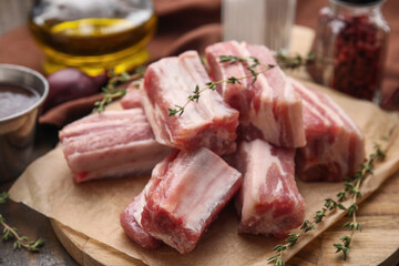 Cut raw pork ribs with thyme on table, closeup