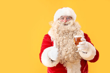 Santa Claus with glass of beer showing thumb-up on yellow background