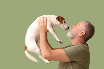 Senior man playing with cute dog on green background