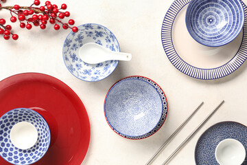 Bowls with plates, chopsticks and berries branch on white grunge background. Chinese table setting