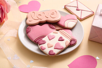 Plate with sweet cookies and decor on yellow background. Valentine's Day celebration