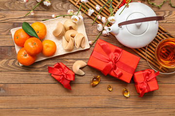 Gift boxes with teapot, fortune cookies and mandarins on wooden background. New Year celebration