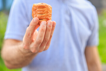 A man's hand holds a mini puff pastry with cheese, snack and fast food concept. Selective focus on...