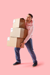 Young man carrying parcels on pink background