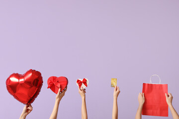 Women with balloon, gifts, credit card and shopping bag on lilac background. Valentine's Day...