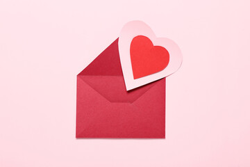 Composition with envelope and red paper heart on pink background. Valentine's Day celebration