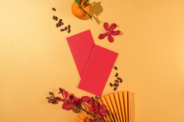 Two red envelopes, a paper fan, fresh orchids and tangerines are arranged on a pastel background. Blank space for text design with Tet theme.