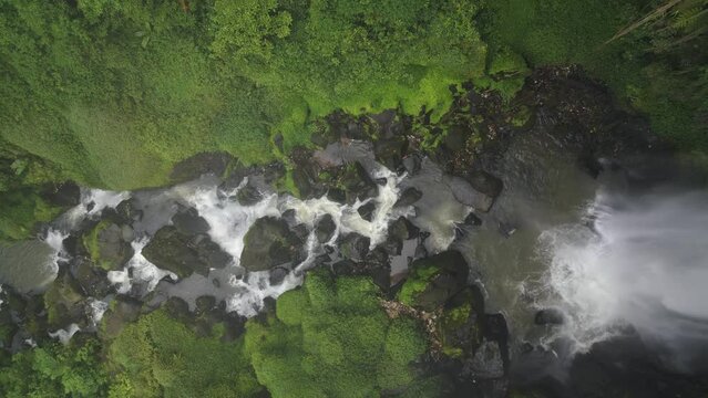 Aerial top down drone descending vertically into the Waterfall and river stream  of Penatapan Forest at Berastagi, North Sumatera, Indonesia. Beautiful nature scenery