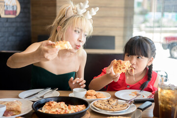 Happy mother and daughter Having Pizza in a Restaurant. Happy family craving for fast food meal