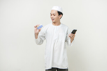 handsome asian man holding credit card and mobile phone on isolated background