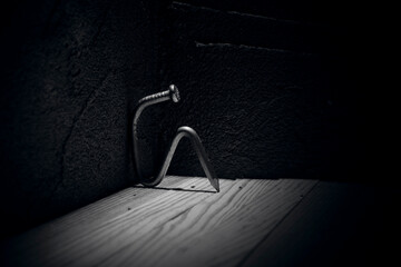 The metal nail depicts a man sitting against a wall in a state of depression