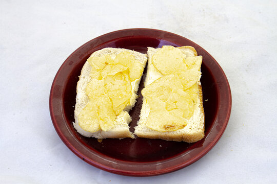 Potato crisps on a slice of buttered white bread on a plate isolated on a clear background with copy space