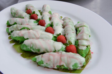pisang ijo ice or green banana ice a tradisonal snack foods from ethnic Bugis or Makassar made of ripe banana pancakes wrapped in pandan leaf extract gravy with fla, syrup,milk and peanut powder
