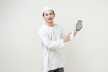 happy asian muslim showing blank phone screen and give pointing finger gesture. People religious Islam lifestyle concept. celebration Ramadan and ied Mubarak. on isolated background.