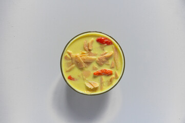 A typical Indonesian food is young bamboo vegetables or "lodeh rebung" with the addition of red chillies, cooked in coconut milk and yellow in color on bowl. closeup, top view
