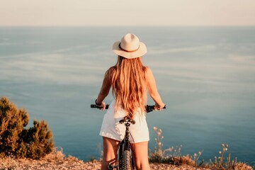 A woman cyclist on a mountain bike looking at the landscape sea. Adventure travel on bike.