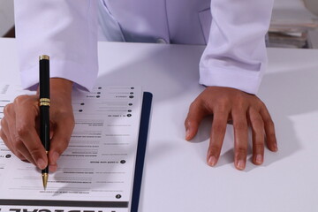 Close up of the ears of a professional female doctor in uniform taking notes in a notebook Medical therapist filling out medical documents. Clipboard. Patient form. Illness history, prescription