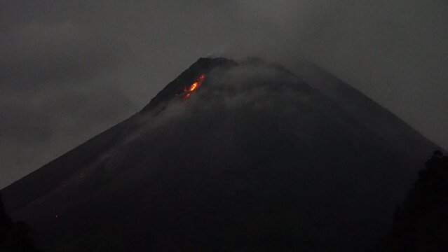 flow of incandescent lava fire bon Mount Merapi which is partially covered by thick fog