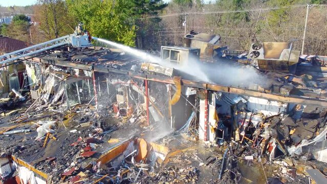 Fire Fighter Blasting Water at Burnt Building on the Brink of Collapsing