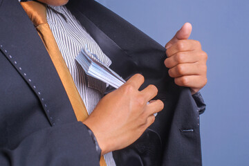 Man in a suit placing money in his jacket pocket. Concept for corruption, finance profit, bail,...
