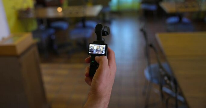 Close-up shot of male hand operating and using DJI Osmo Pocket 3 Gimbal Camera indoors.