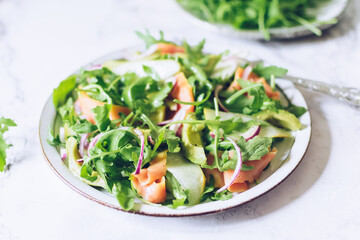 Healthy salad with arugula, smoked salmon, pear, avocado and red onion