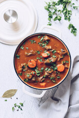 Beef meat stewed with potatoes, carrots and spices in cast iron pot