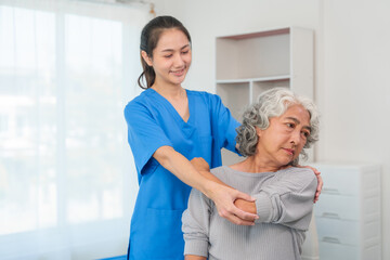 A young Asian nurse is assisting an elderly Asian woman with a grey hair during a physical therapy...
